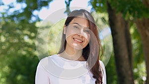 Happy smiling pretty Asian woman with a smile on her face looking at the camera in broad daylight in the park, natural sunlight,