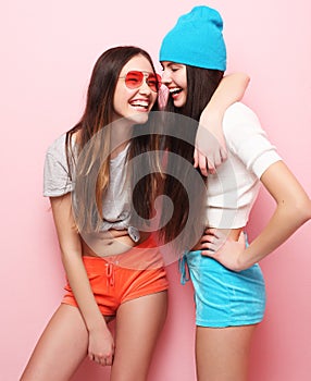 Happy smiling pretty teenage girls or friends hugging over pink