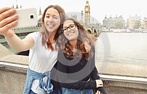 Happy smiling pretty teenage girls taking selfie at Big Ben, London