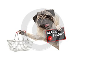 Happy smiling pug puppy dog, with wire metal shopping basket and Black Friday Sale sign, behind white banner