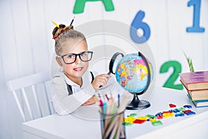 Happy smiling pupil at the desk. Child in the class room with pencils, books. Kid girl from primary school. first day of