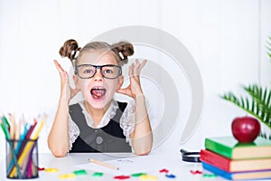 Happy smiling pupil at the desk. Child in the class room with pencils, books. Kid girl from primary school. first day of