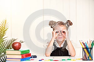 Happy smiling pupil at the desk. Girl in the class room with pen