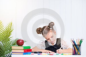 Happy smiling pupil at the desk. Girl in the class room with pen