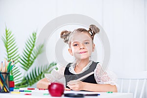 Happy smiling pupil at the desk. Girl in the class room with pen