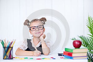 Happy smiling pupil at the desk. Girl in the class room with pencils, books. Kid girl from primary school. first day of