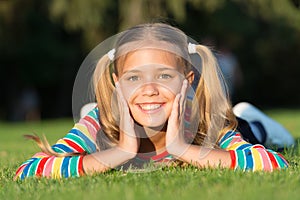 Happy smiling pupil. Have fun. Girl cute kid laying green grass. Healthy emotional happy kid relaxing outdoors. What