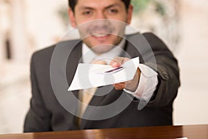 Happy smiling receptionist in hotel giving key to guest and papers to sign