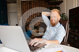 Happy smiling redhead bearded man enjoys freelance work