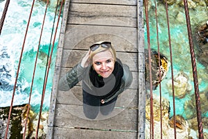 Happy smiling and relaxing woman on an day trip standing on a old wooden hanging bridge