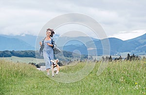 Happy smiling running beagle dog portrait with tongue out and owner female jogging by the mounting meadow grass path. Walking in n photo