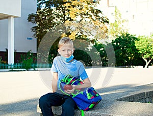 Happy smiling schoolboy on the background of school. School boy wearing medical face mask to health protection. Back to school.