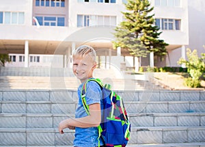 Happy smiling schoolboy with backpack on the background of school. Back to school. Learning concept