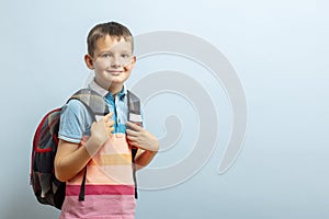 Happy smiling schoolboy with backpack on blue background. School concept. Back to school