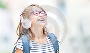 Happy smiling schoolgirl with dental braces and glasses listening music from headphones..  Orthodontist and dentist concept