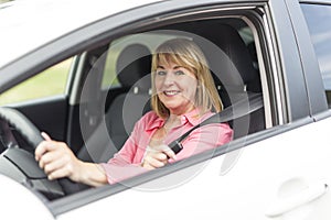 Happy and smiling senior woman in black car