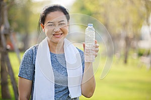 Happy smiling senior woman holding bottle after drink water exercise in garden.