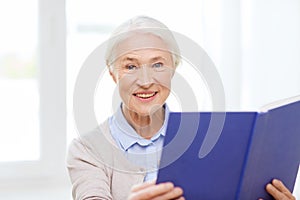 Happy smiling senior woman reading book at home