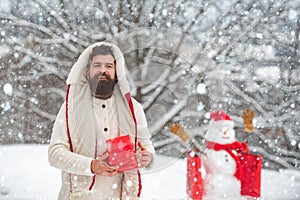 Happy smiling snow man on sunny winter day with Happy father. Cute little snowman and bearded man with shopping bag