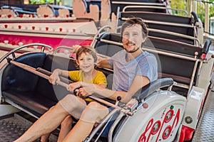 happy smiling son and his handsome father spending fun time together at amusement park