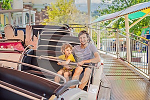happy smiling son and his handsome father spending fun time together at amusement park