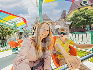 happy smiling son and his mother spending fun time together at amusement park