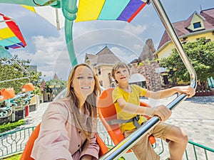 happy smiling son and his mother spending fun time together at amusement park