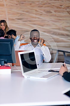 Happy smiling successful African American businessman in in a modern bright startup office indoors