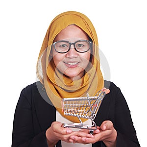 Happy smiling sucessful Asian muslim woman showing mini shopping trolley on her hand