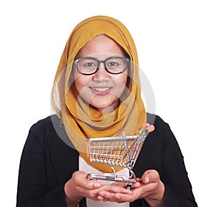 Happy smiling sucessful Asian muslim woman showing mini shopping trolley on her hand photo