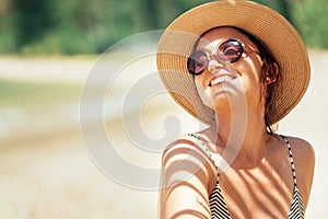 Happy smiling sun buthing woman in straw hat portrait. Palm tree shadows on the body. Health tanning concept