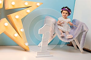 Happy smiling sweet baby girl sitting on armchair with shining light star, Birthday girl, One year old