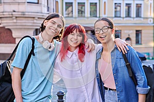 Happy smiling teenage friends hugging, looking at camera outdoor, on city street