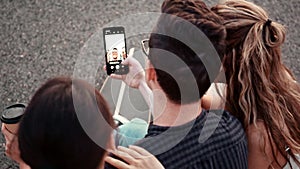 Happy smiling teenage friends laughing outside at something in smartphone or mobile phone. Three young multiracial