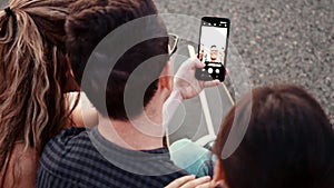 Happy smiling teenage friends laughing outside at something in smartphone or mobile phone. Three young multiracial