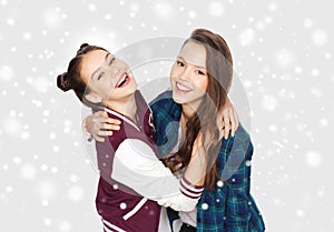 Happy smiling teenage girls hugging over snow