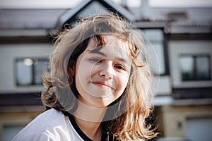 Happy smiling teenager girl with curly hair outdoors