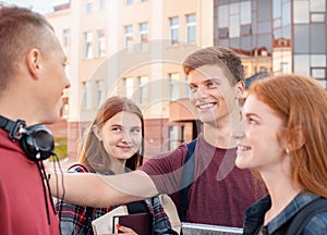 Happy smiling teenager students chatting with each others against background of the university