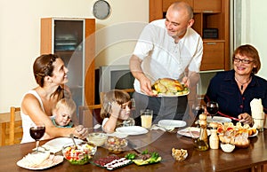 Happy smiling three generations family eating chicken with wine