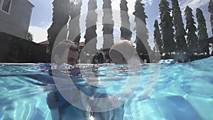 Happy smiling toddler is diving under water with father