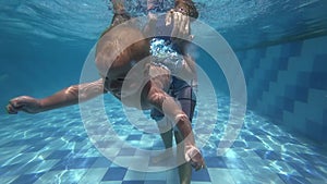 Happy smiling toddler is diving under water with father