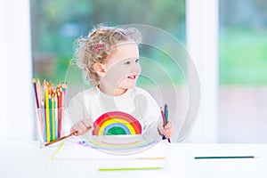 Happy smiling toddler girl drawing a rainbow