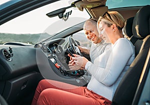 Happy smiling two young adulds couple using smartphone navigation inside car during auto jorney.They are laughing during road trip