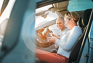 Happy smiling two young adulds couple using smartphone navigation inside car during auto jorney.They are laughing during road trip photo