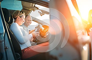 Happy smiling two young adulds couple using smartphone navigation inside car during auto jorney.They are laughing during road trip