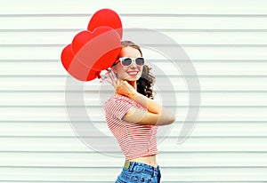 Happy smiling woman with air balloons heart shape having fun over white