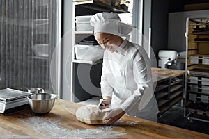 Happy smiling woman baker shaping dough for cooking bread, pizza or pastry