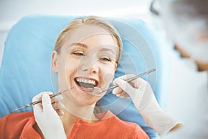 Happy smiling woman is being examined by dentist at dental clinic. Healthy teeth and medicine, stomatology concept