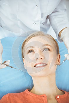 Happy smiling woman is being examined by dentist at dental clinic. Healthy teeth and medicine, stomatology concept