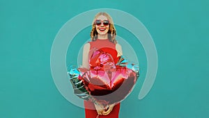 Happy smiling woman with bunch of red heart shaped balloons on blue background